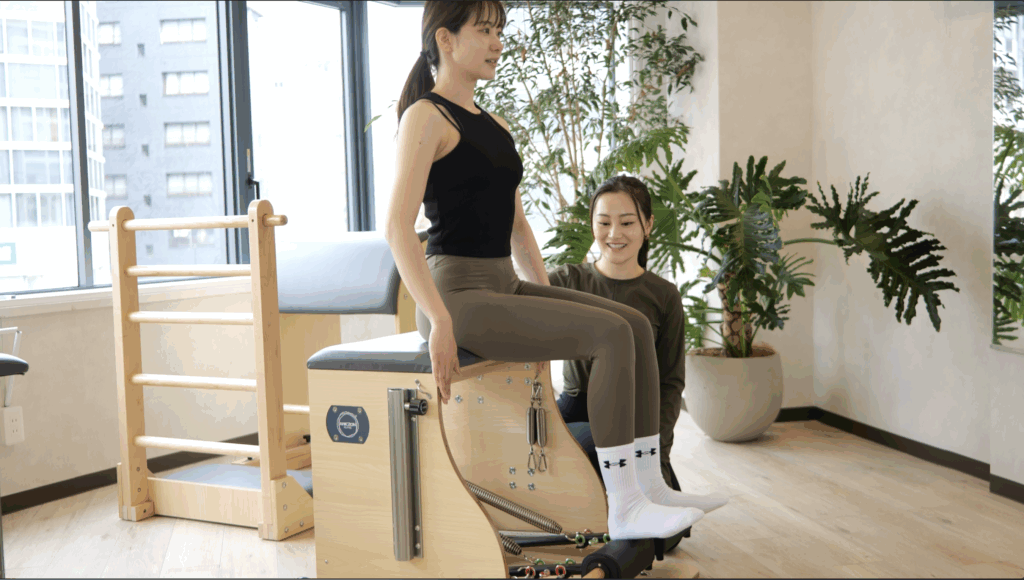 インストラクターの指導を受けてピラティスをする女性
