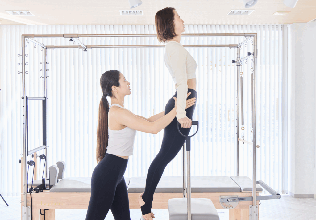 インストラクターとマシンピラティスをする女性