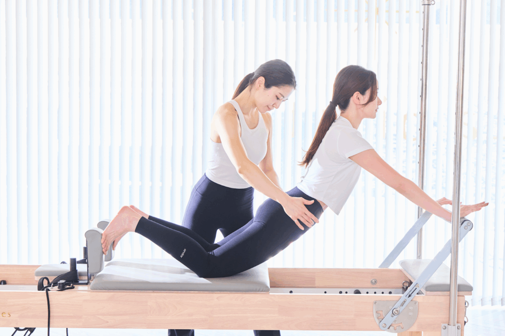 インストラクターがマシンピラティスをする女性をサポートしている様子