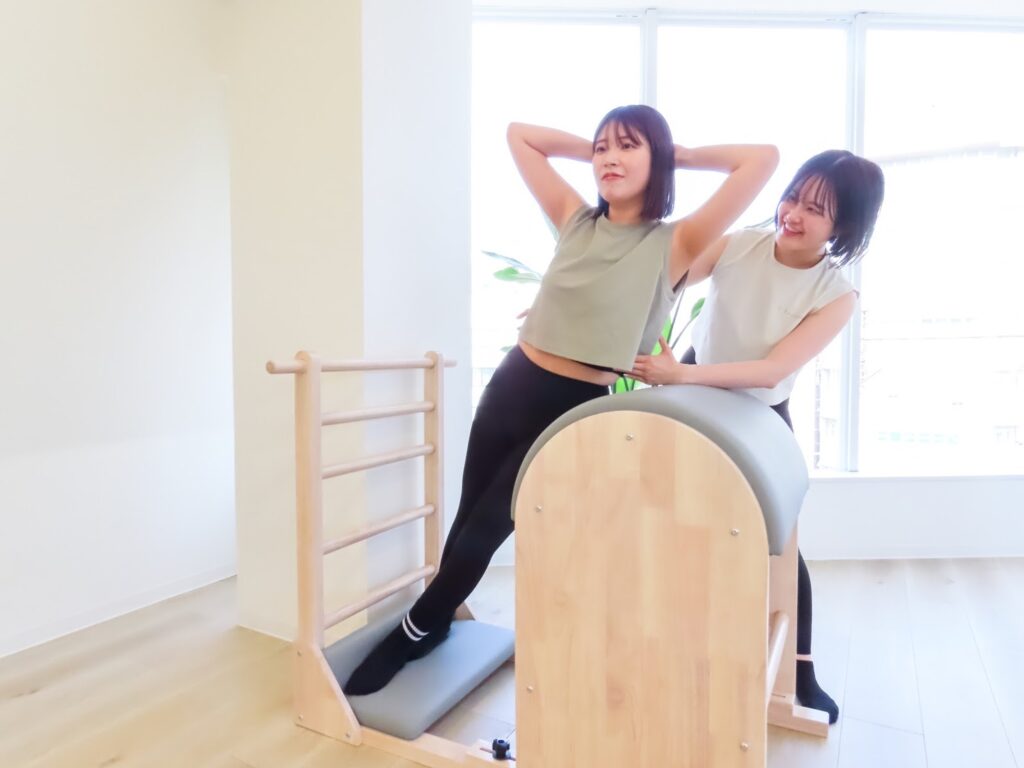 体幹を鍛える女性をインストラクターがサポートしている様子