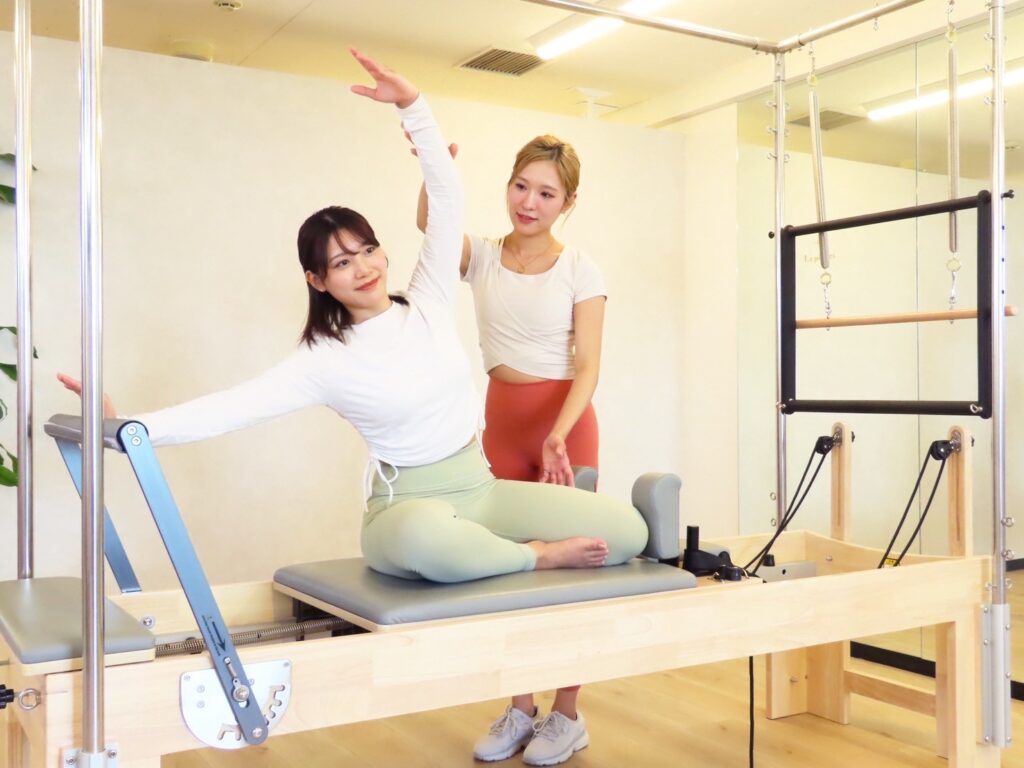 La pilatesのパーソナルレッスンでインストラクターがサポートしている様子