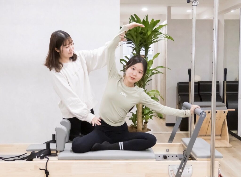 La pilatesのマンツーマンレッスンでインストラクターがサポートしている様子